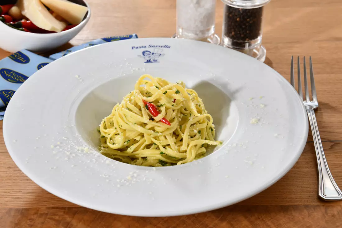 Tagliarini mit Petersilie, Knoblauch, Olivenöl und Chili, bestreut mit geriebenem Käse.