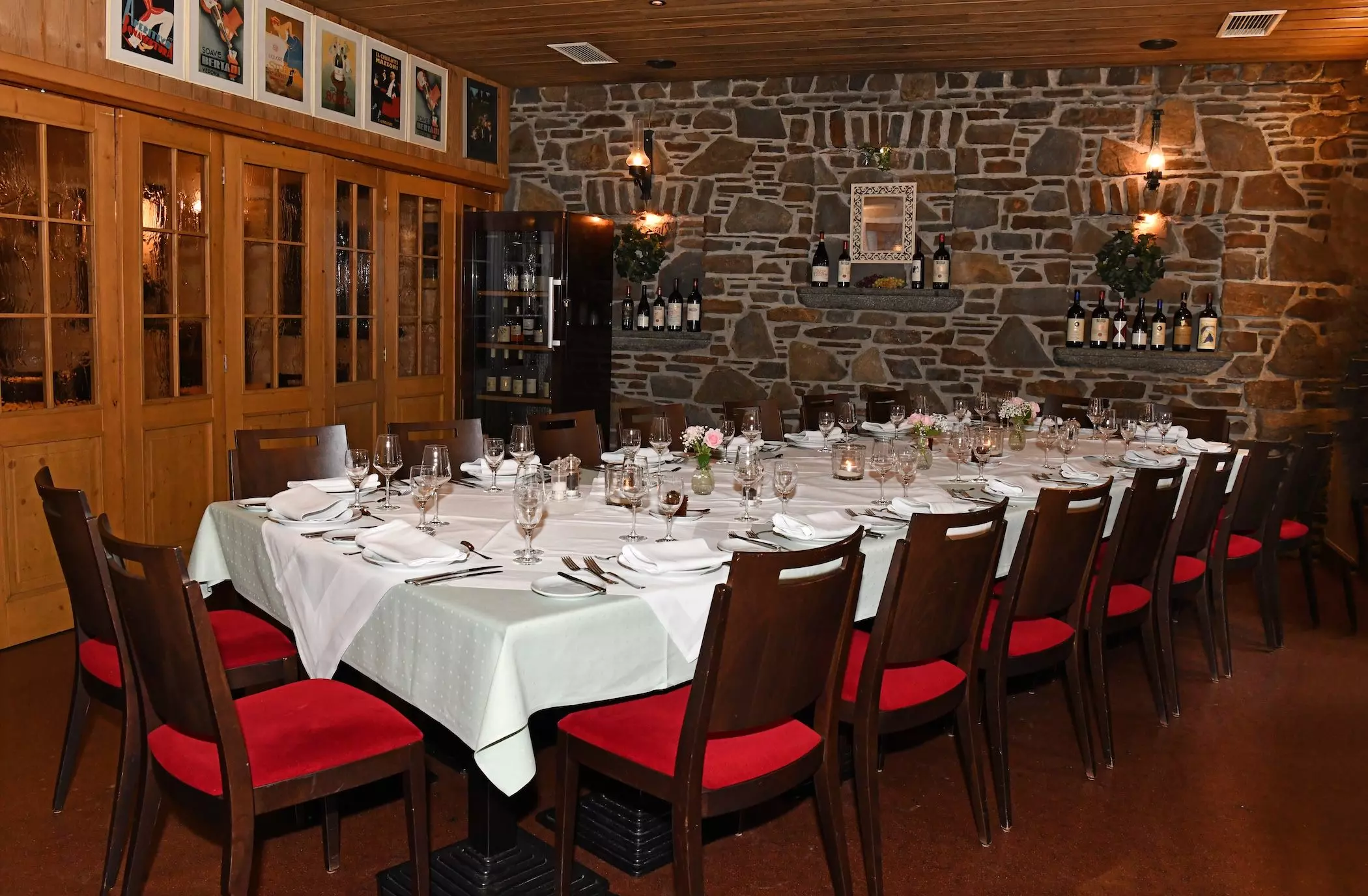 Ein langer Tisch ist weiß eingedeckt, mit Gedecken, Gläsern und einer kleinen Blumendekoration.